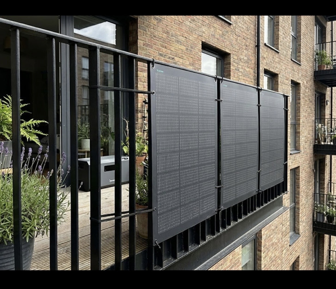 Plug-in solar panels clamped to a balcony railing on a UK apartment block — no drilling required
